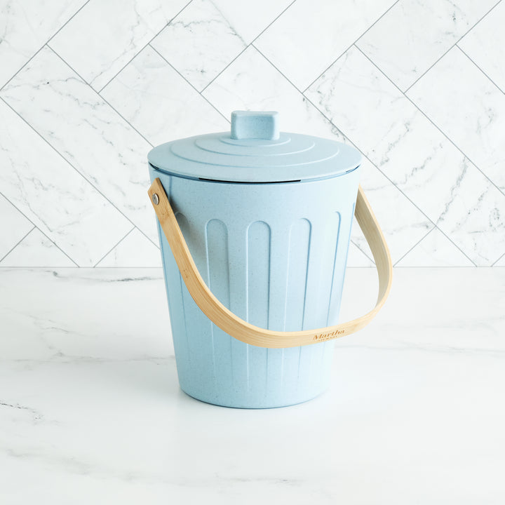 Light blue trash bin with a beige handle on a white background